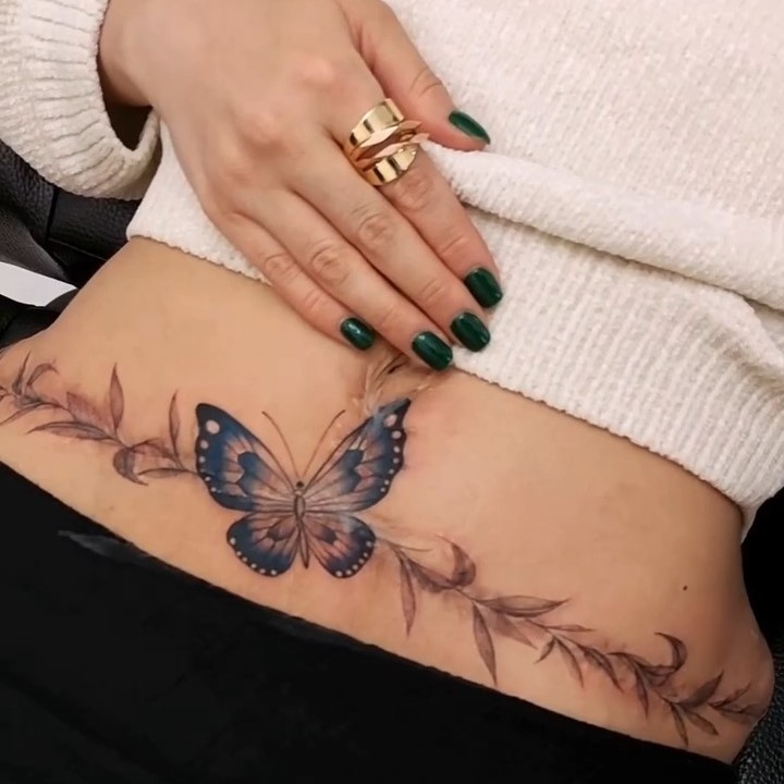 تاتو پروانه و شاخ و برگ روی اسکار شکم